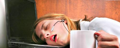 photo of woman sleeping at desk with coffee in hand